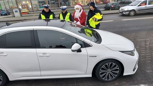Policjantka z Mikołajem przy samochodzie.