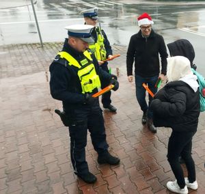 Policjanci rozdają odblaski na ulicy.