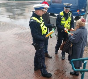 Policjanci rozdają odblaski na ulicy.