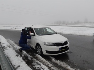 Tor łódź, samochód stoi na torze, mężczyzna z kamerą stoi przy samochodzie.