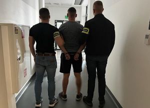 Policjanci prowadzą zatrzymanego.