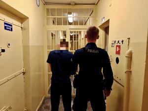 Policjant prowadzi zatrzymanego.