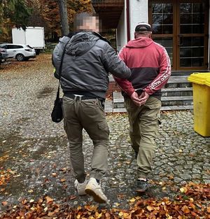 Policjant prowadzi zatrzymanego.