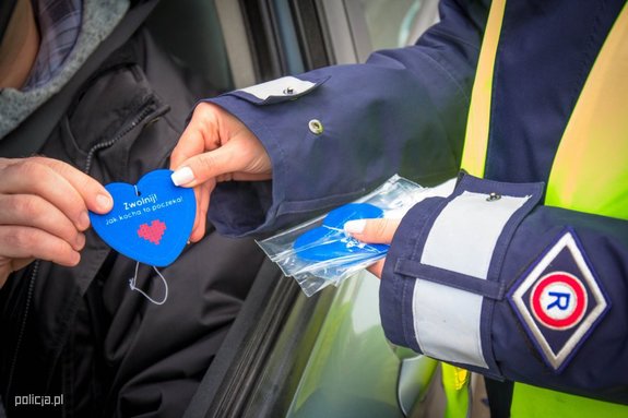 Policjant wręcza niebiesko serduszko.