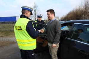 Policjanci dają ulotkę kierowce.