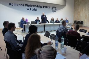 Sala konferencyjna goście i kierownictwo policji oraz słuchacze za stołem.