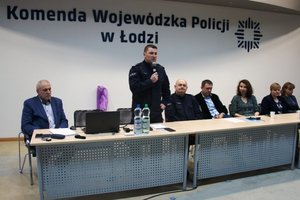 Sala konferencyjna goście i kierownictwo policji oraz słuchacze za stołem.