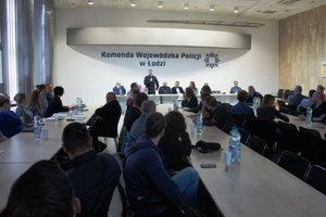 Sala konferencyjna goście i kierownictwo policji oraz słuchacze za stołem.