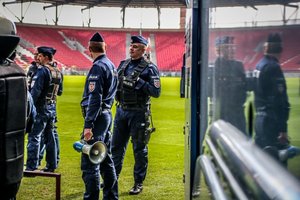 Policjanci stoją na stadionie.