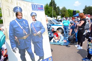 Plansza z policjantami w historycznych mundurach do robienia zdjęć z otworami na głowy, pozuje dwójka dzieci.