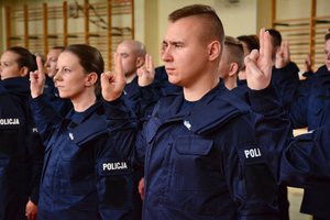 grupa umundurowanych policjantów w trakcie ślubowanie i składania przysięgi.maja podniesione dłonie.