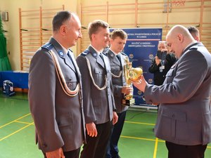 komendant odbiera puchar od 3 osobowej delegacji policjantów.