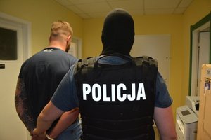 policjant konwojuje zatrzymanego.