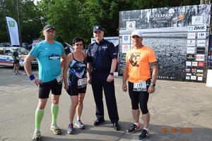 3 biegaczy w strojach sportowych i umundurowany policjant pozują do zdjęcia