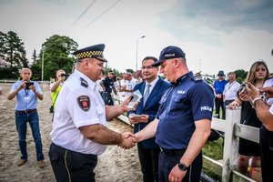 komendant straży miejskiej wręcza statuetkę z cy komendanta wojewódzkiego policji w Łodzi , obaj w mundurach.