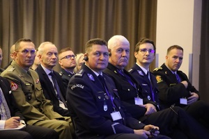 Zdjęcie przedstawia patrzących w kierunku fotografa siedzących uczestników konferencji.
