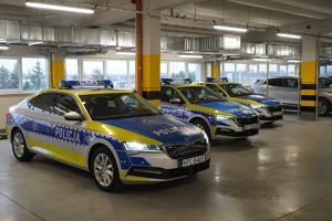 Zdjęcie przedstawia trzy stojące obok siebie w zamkniętym garażu oznakowane radiowozy marki Skoda.