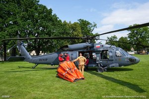 Zdjęcie przedstawia helikopter zlokalizowany na trawniku, do helikopter został przytwierdzony kosz bambi bucket.