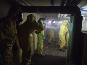 Zdjęcie przedstawia uczestników szkolenia ubranych w żółte kombinezony ochronne w trakcie realizowania zadań szkoleniowych