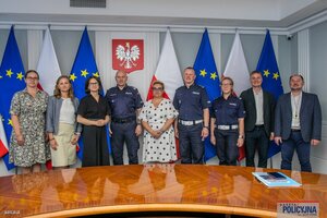 Zdjęcie przedstawia uczestników uroczystego spotkania z okazji podpisania umów o dofinansowanie dla trzech projektów mających na celu poprawę bezpieczeństwa w ruchu drogowym: panią Joannę Lech, pana nadinsp. dr Rafała Kochańczyka oraz dyrektorów komórek organizacyjnych Komendy Głównej Policji odpowiedzialnych za przygotowanie i realizację przedsięwzięć: Zastępcę Dyrektora Biura Ruchu Drogowego KGP insp. Leszka Jankowskiego, Dyrektor Biura Finansów Magdalenę Świderską, a także kadrę kierowniczą: kierownik projektów Biura Ruchu Drogowego i naczelnik wydziału innowacji i transportu BRD KGP mł. insp. Magdalenę Malinowską - Miąsek, Zastępcę Naczelnika Wydziału Zamówień Publicznych i Funduszy Pomocowych Biura Finansów KGP Roberta Skibińskiego oraz przedstawicieli Centrum Unijnych Projektów Transportowych i KGP.