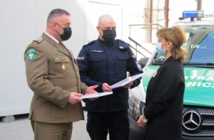 Policjant oraz strażnik graniczny stojący obok kobiety