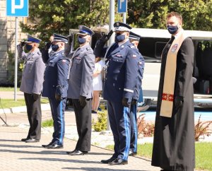 Umundurowani policjanci stojący w kilku szeregach. Obok stoi ksiądz