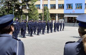 Dwaj umundurowani policjanci idący przed szeregiem policjantów