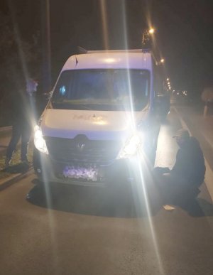 Policjant operacyjny stoi przy zatrzymanym mężczyźnie, który leży obok kradzionego samochodu dostawczego