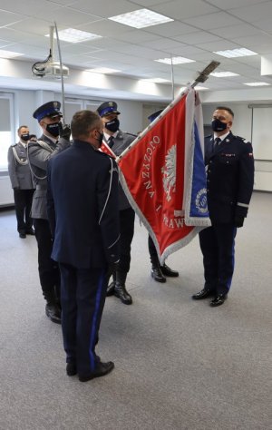 Umundurowani policjanci stojący przed sztandarem