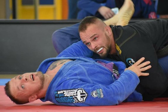 Dwóch mężczyzn podczas walki na macie w BJJ