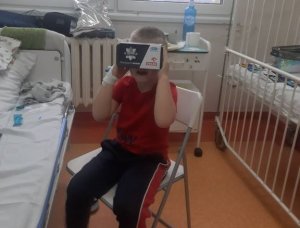 Dziecko siedzące na szpitalnym krześle z okularami vr przy twarzy