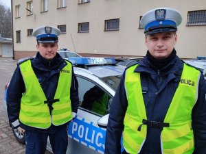Dwóch policjantów stojących obok radiowozu