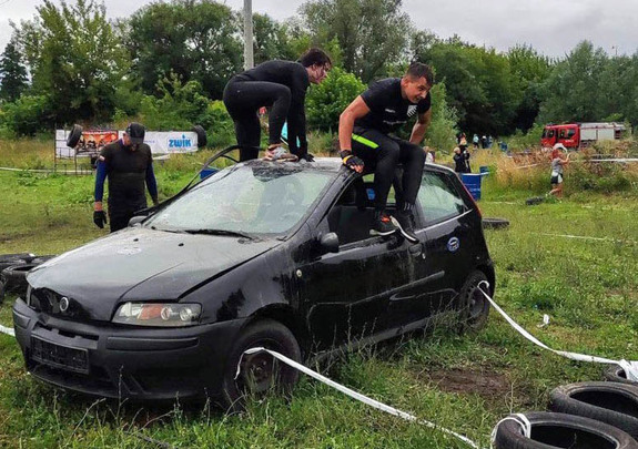 Osoby w strojach sportowych przeskakują samochód