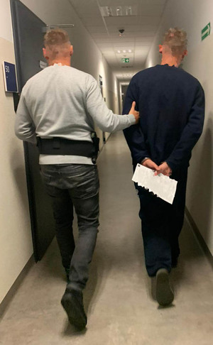 Zatrzymany mężczyzna prowadzony przez policjanta