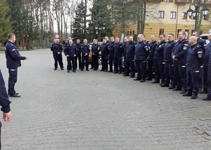 Umundurowani policjanci stojący przed budynkiem