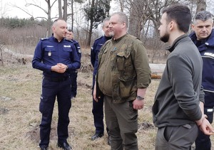 Umundurowani policjanci stojący na leśnej polanie