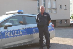 Umundurowany policjant stojący przy radiowozie