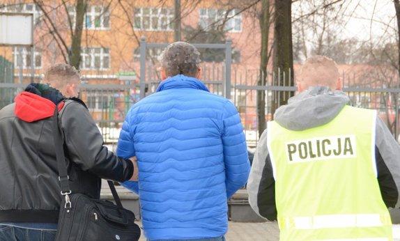 Mężczyzna prowadzony przez policjantów