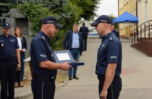 Umundurowani policjanci stojący przed budynkiem posterunku