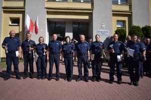 Umundurowani policjanci stojący przed budynkiem