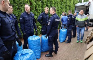 Policjanci pakujący na ciężarówkę worki z zakrętkami