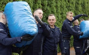 Policjanci pakujący na ciężarówkę worki z nakrętkami