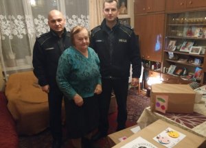 Umundurowani policjanci wraz z osobą, której dowieźli świąteczną paczkę