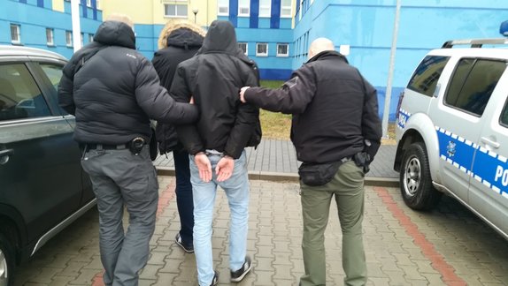 mężczyzna prowadzony przez policjantów