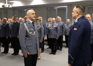 Umundurowani policjanci stojący w szeregu w sali