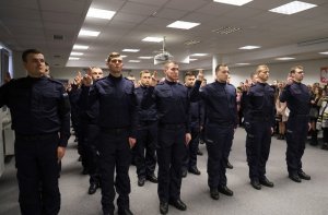 Umundurowani policjanci stojący w szeregu w sali