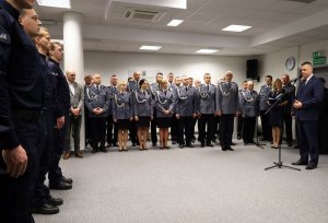 Umundurowani policjanci stojący w szeregu w sali