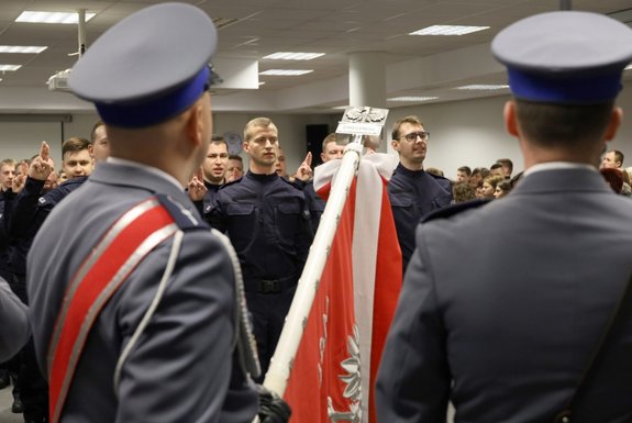 Umundurowani policjanci stojący w szeregu przed sztandarem