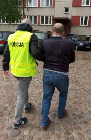 Jeden z zatrzymanych mężczyzn prowadzony przez policjantów