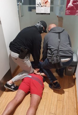 Policjanci prowadzą zatrzymanego poszukiwanego